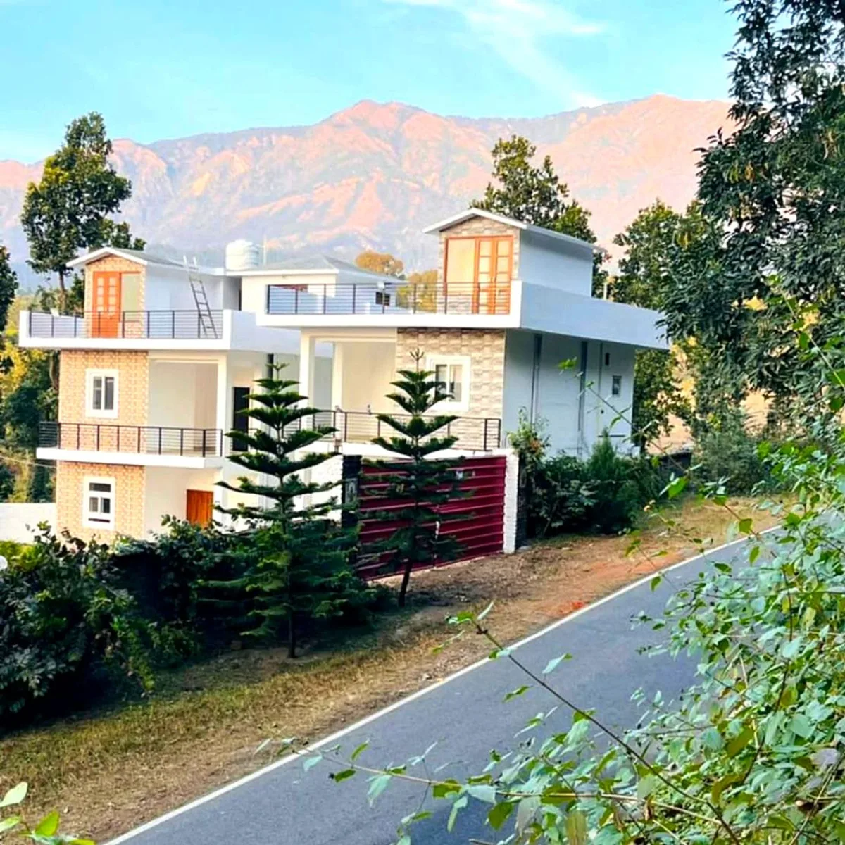 Farmhouse villa with balconies among pine trees, mountains in the distance