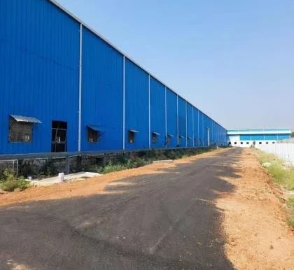 Long blue prefabricated warehouse beside a paved access road